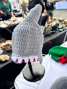 a knitted hat on top of a table with people in the background at an outdoor market