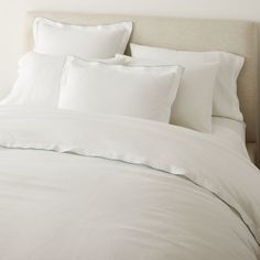 a bed with white sheets and pillows on it