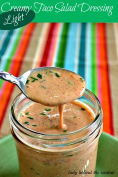 a spoon full of creamy taco salad dressing on a green plate with a striped cloth