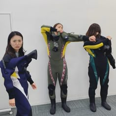 three women in wetsuits standing next to each other