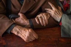 two older people sitting at a table with their hands on each other