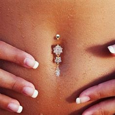 a woman's belly with jewelry on it and her hands behind her back,