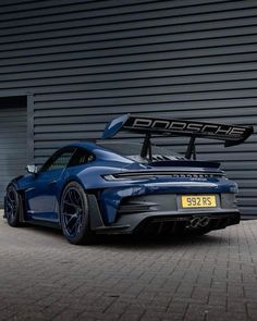 a blue sports car parked in front of a garage door with a surfboard on it's roof