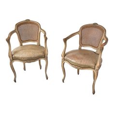 a pair of chairs with caned back and armrests in gold colored wood