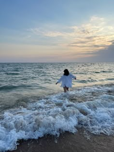 a woman standing in the ocean with her arms outstretched