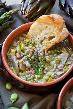 a bowl filled with soup next to asparagus and bread