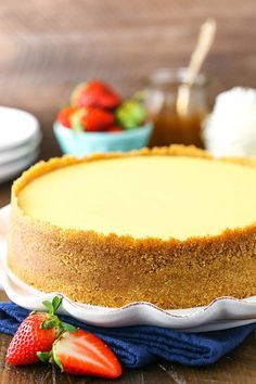 a cheesecake sitting on top of a white plate with strawberries next to it