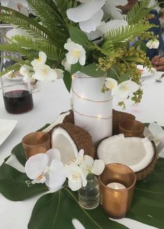 the table is set with white flowers and coconuts, candles, and other items