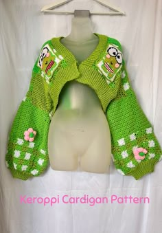 a green knitted sweater with cartoon characters on the front and back, sitting on a mannequin head