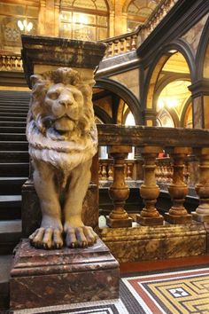 a lion statue sitting on top of a marble block in front of a stair case