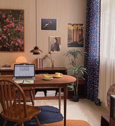 a laptop computer sitting on top of a wooden table in a living room next to a window