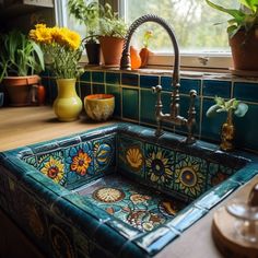 a sink in a kitchen with flowers and potted plants on the window sill