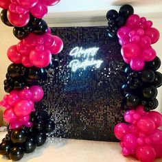 a black and pink balloon arch with the words happy birthday on it in front of a sequin backdrop