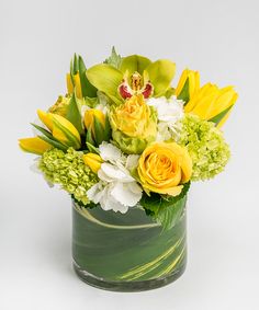 a green vase filled with yellow and white flowers