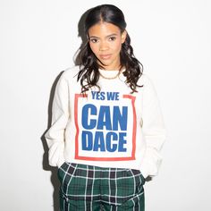 a young woman poses in front of a white wall wearing a sweatshirt that says yes we can dance