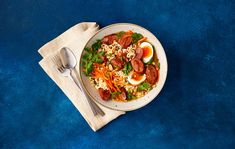 a white plate topped with pasta, meat and veggies next to a fork