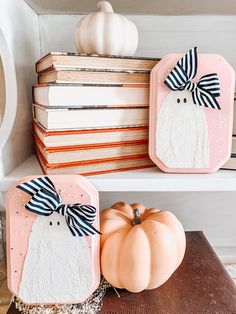 two decorative pumpkins sitting on top of a wooden table next to books and a white pumpkin