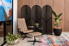 a living room area with chairs, plants and a flat screen tv on the wall