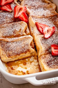 french toast with powdered sugar and strawberries in a casserole dish, ready to be eaten