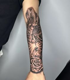 a person with a tattoo on their arm holding a rose and an angel in the middle