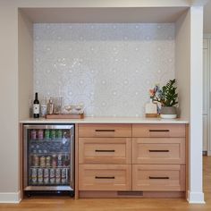 an empty refrigerator in a kitchen next to a counter with bottles and glasses on it