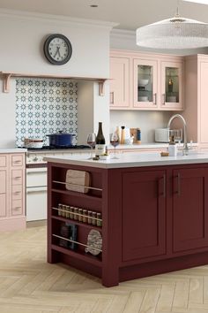 a large kitchen with pink cabinets and white counter tops, an island that has wine bottles on it