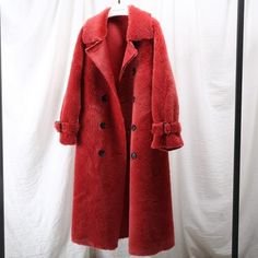 a red coat hanging on a white wall