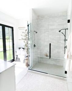 a bathroom with a walk in shower next to a white counter top and black doors