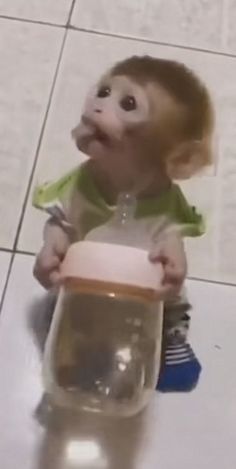 a baby doll sitting on the floor with a jar in it's hand and looking up