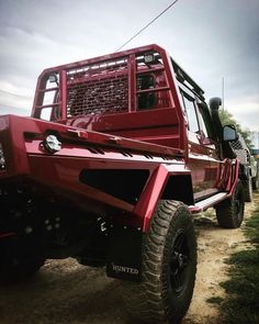 a red truck parked on top of a dirt road