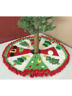 a decorated christmas cake on a table with a tree in the center and decorations around it