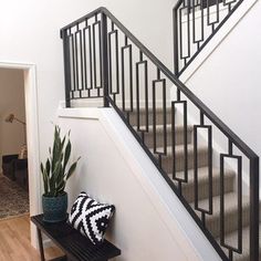 a black and white pillow sitting on top of a bench next to a stair case