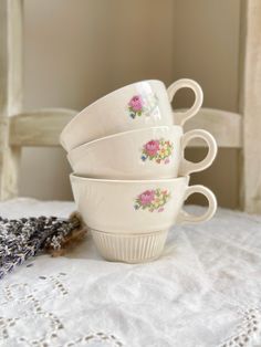 four white cups sitting on top of a table next to lavenders and a lace doily