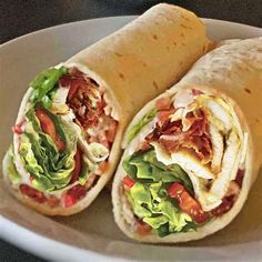 two burritos on a plate with lettuce and tomatoes