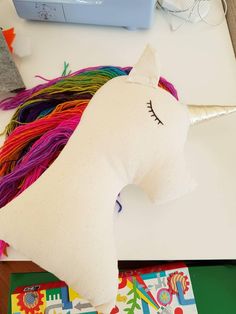 a white stuffed unicorn sitting on top of a table