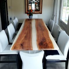 a dining room table with white chairs and a large wooden slab in the center surrounded by windows