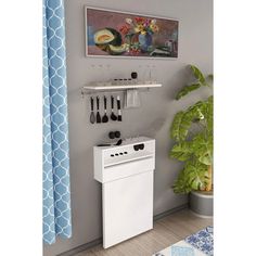 a white stove top oven sitting next to a potted plant and a painting on the wall