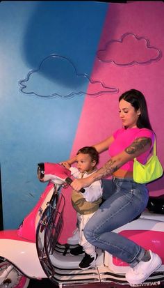 a woman riding on the back of a pink scooter next to a baby