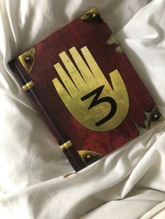 a book with the number three on it laying on top of a white bed sheet