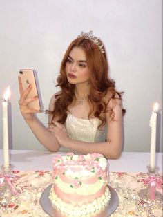 a woman sitting at a table with a cake and cell phone