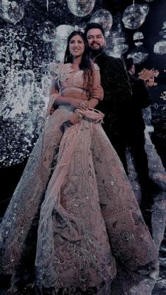 a man and woman standing next to each other in front of a wall with disco balls