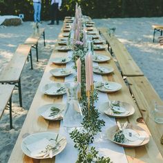 a long wooden table with plates and candles on it