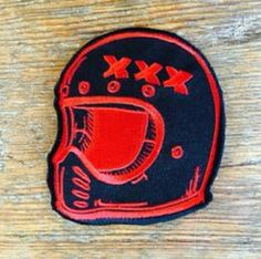 a red and black patch with an image of a helmet on the back of it