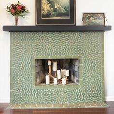 a fire place with candles and pictures on the wall