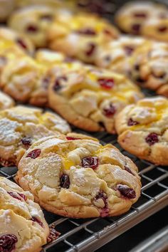 cookies with cranberries and orange zest are cooling on a rack in a bakery