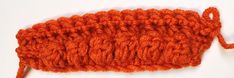 an orange crochet stitch on a white surface