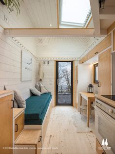 the interior of a tiny home with wood flooring and white painted walls, including a skylight