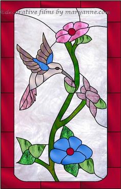 a stained glass window with flowers and a humming bird on it's side, in front of a red brick wall