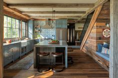 a kitchen with wooden walls and flooring next to an island in the middle of a room