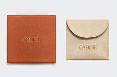 an orange card case with the word cadine in gold foil on it and a tan leather wallet